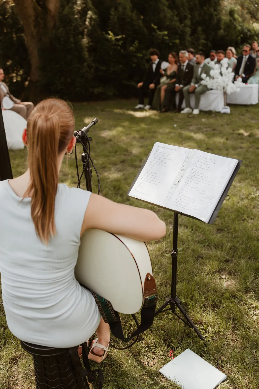 Jasmin mit Gitarre vor den Gästen einer Trauung im Garten